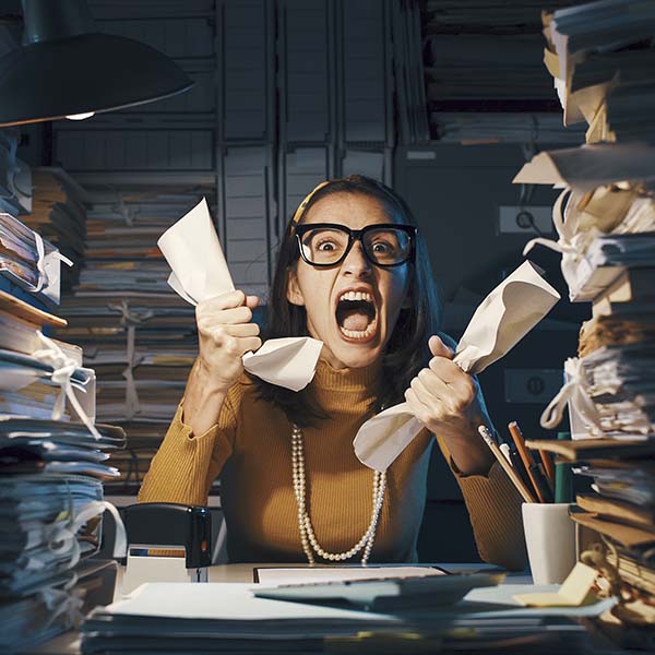 Angry stressed office worker overloaded with paperwork