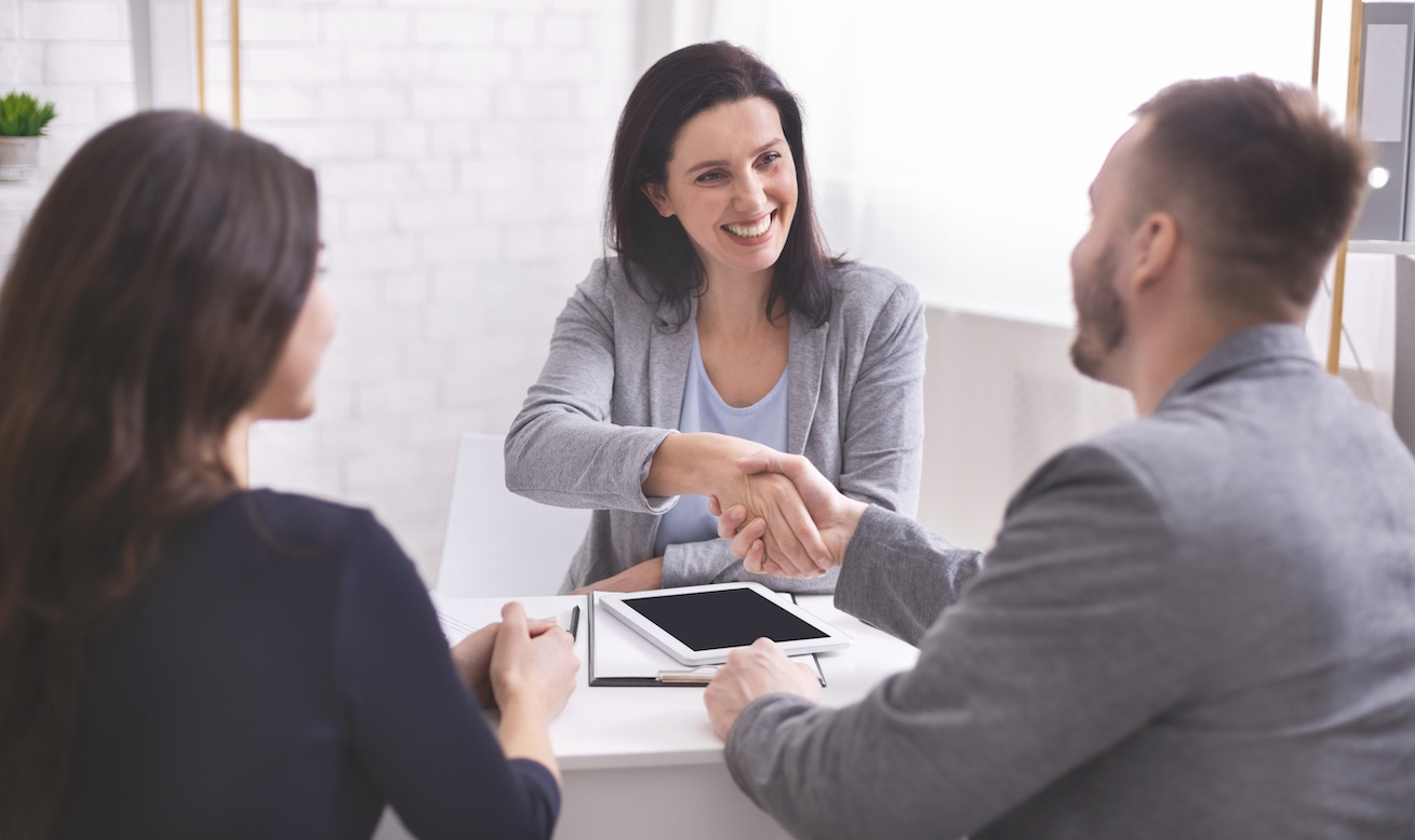 Smiling female insurance broker and young family shaking hands making purchase deal or investment, empty space